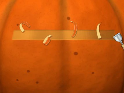 A shaving blade at the end of a pale shaved strip across the pumpkin’s skin, with orange peels curling up off it